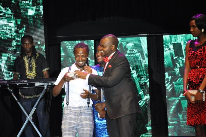 Airtel Uganda's Musa Mayanja hands over a brand new phone to Trace finalist Dan Flavor during the Airtel Trace Music Star finals at Serena Hotel